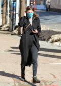 Alexandra Daddario sort avec un pardessus noir par temps venteux à New York