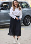 Kelly Brook a l'air chic dans une chemise blanche et une jupe plissée bleu marine alors qu'elle arrive aux Global Radio Studios à Londres, au Royaume-Uni